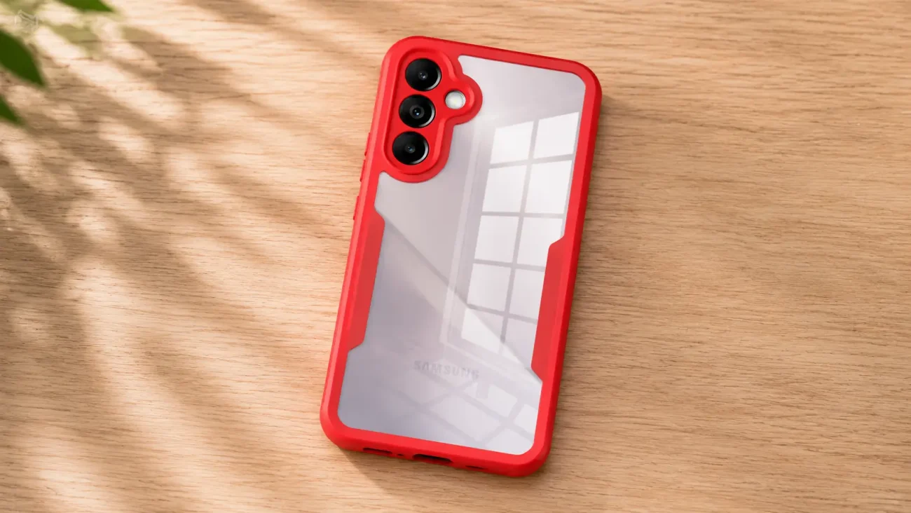 Red protective bumper case around a Samsung smartphone with a triple-camera module resting on a light wood surface, sunlight shadows nearby