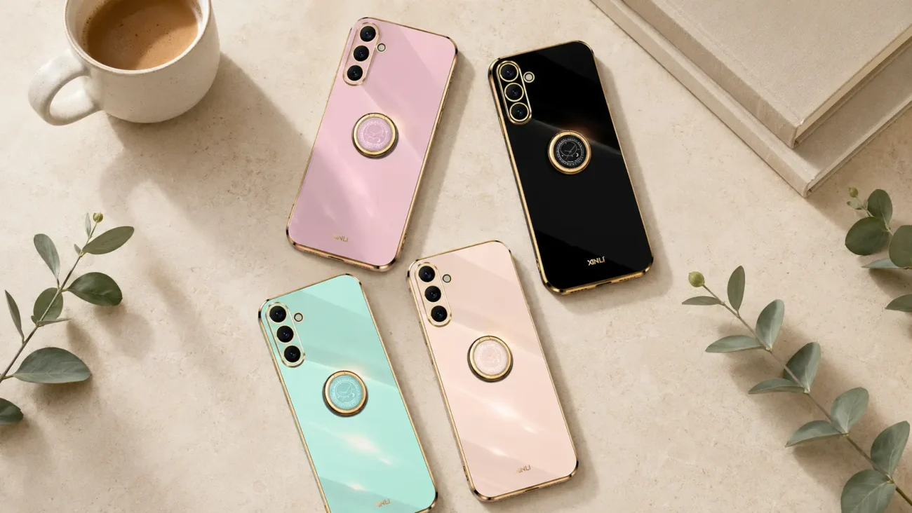 Four glossy smartphones in pink, mint green, beige, and black with gold edges and circular mounts on a beige surface beside a coffee mug and greenery.