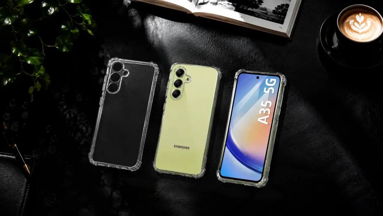 Three Samsung smartphones with clear protective cases laid out on a dark surface beside a plant and a cup of coffee, showcasing different colors and angles.