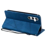 Blue folio-style smartphone case with a tri-camera cutout, shown in a raised stand position, made of textured blue leather with stitched edges and a wrist strap.